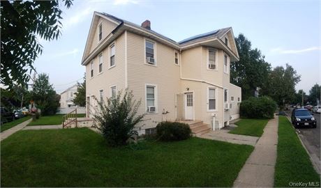 legal three-family home, sold with an additional adjoining lot, offers strong r